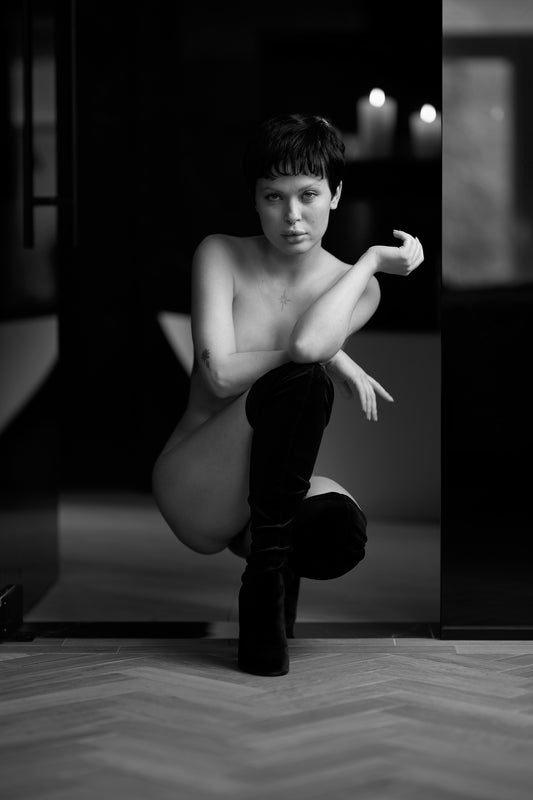 Black and white photo of a person posing in a room with a blurred background
