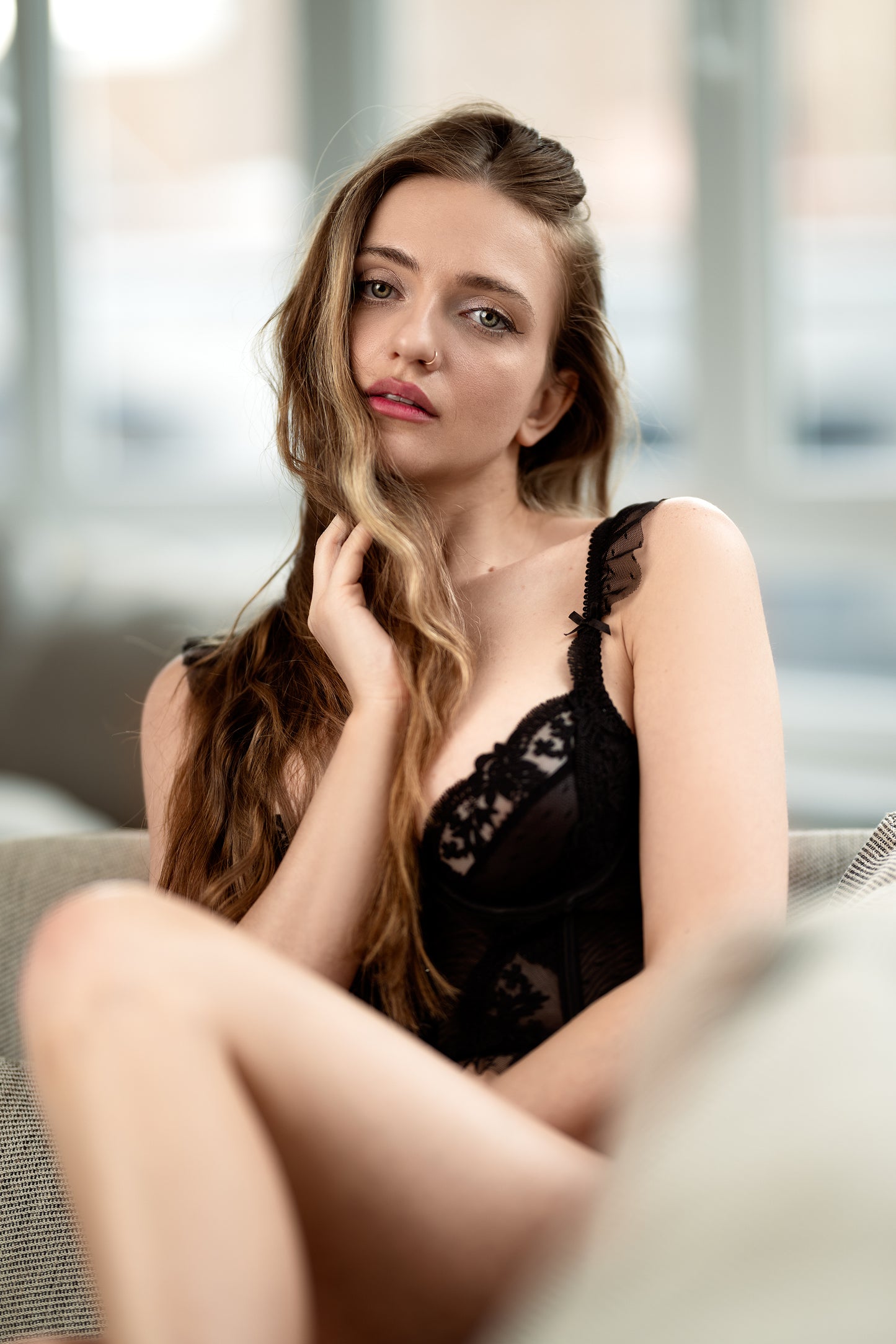 Woman in black lace lingerie sitting on a couch with a blurred background